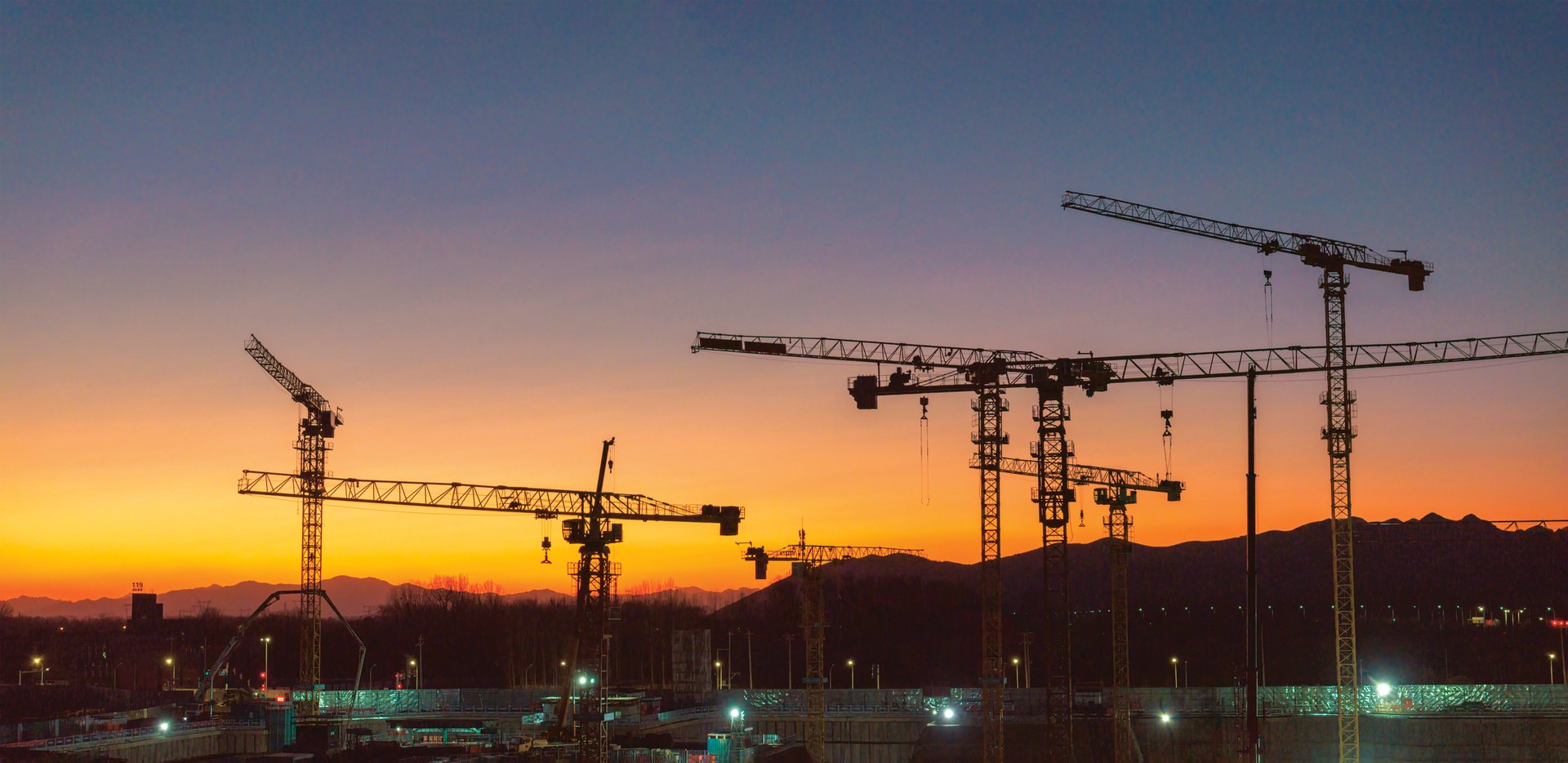 Chantier de construction au crépuscule, grues en silhouette
